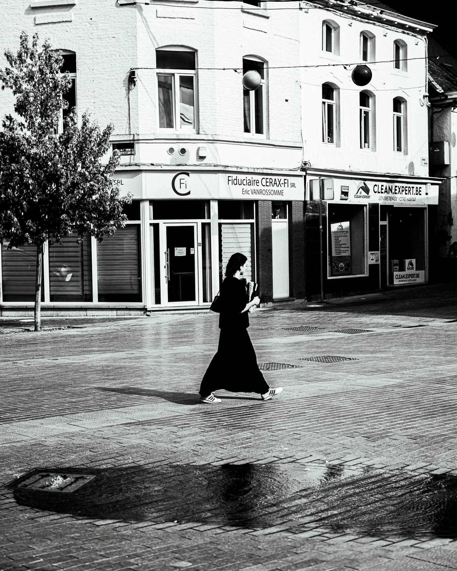 Silhouette féminine traversant une place lumineuse