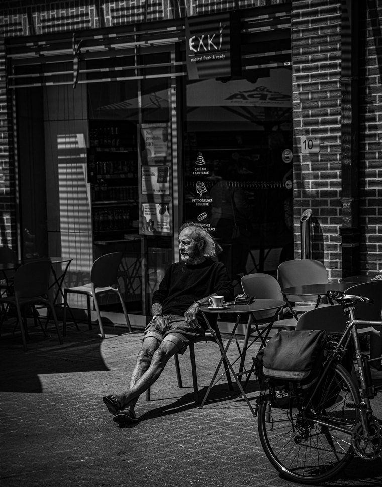 Homme assis près d’un vélo et d’une terrasse