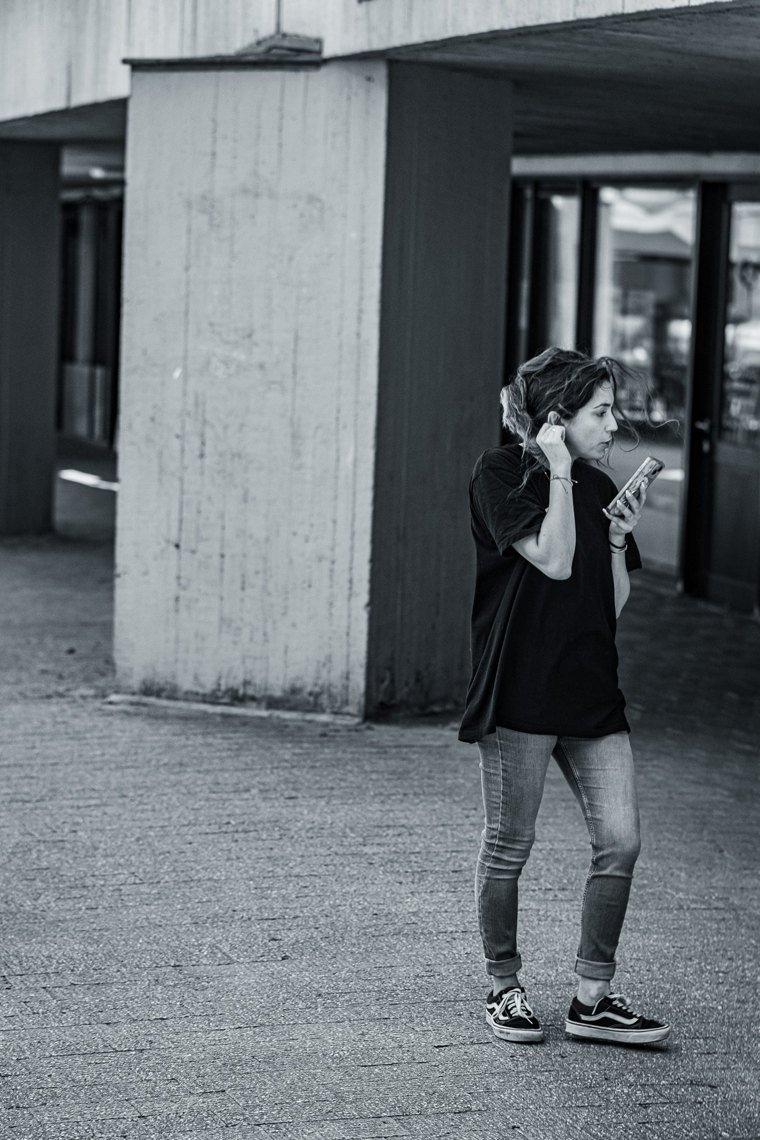Jeune femme avec écouteurs près d’un mur de béton