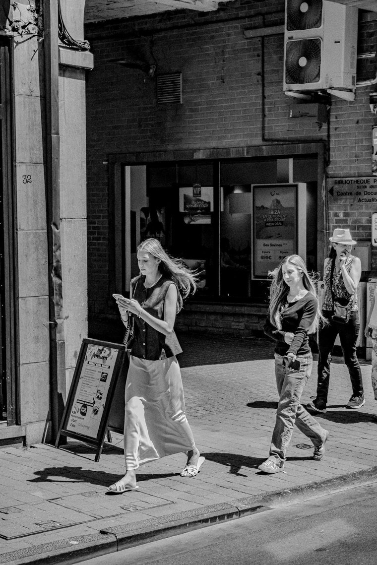 Passante regardant son téléphone près d’un panneau