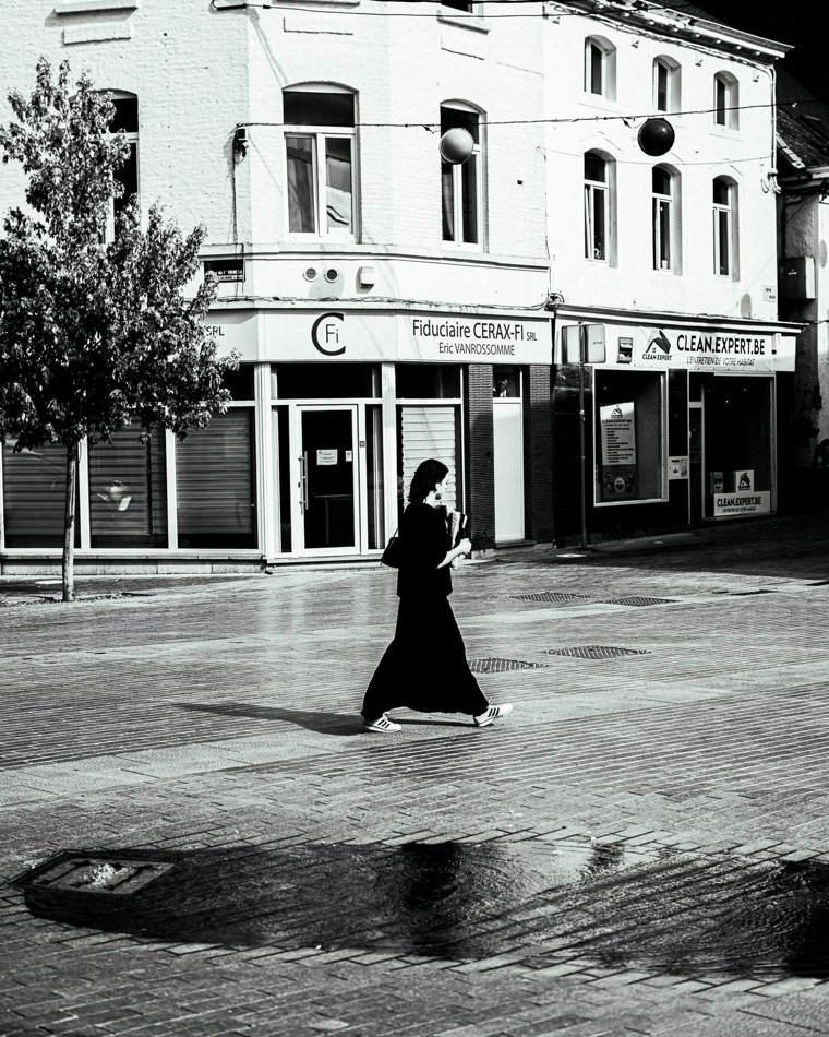 Silhouette féminine traversant une place lumineuse
